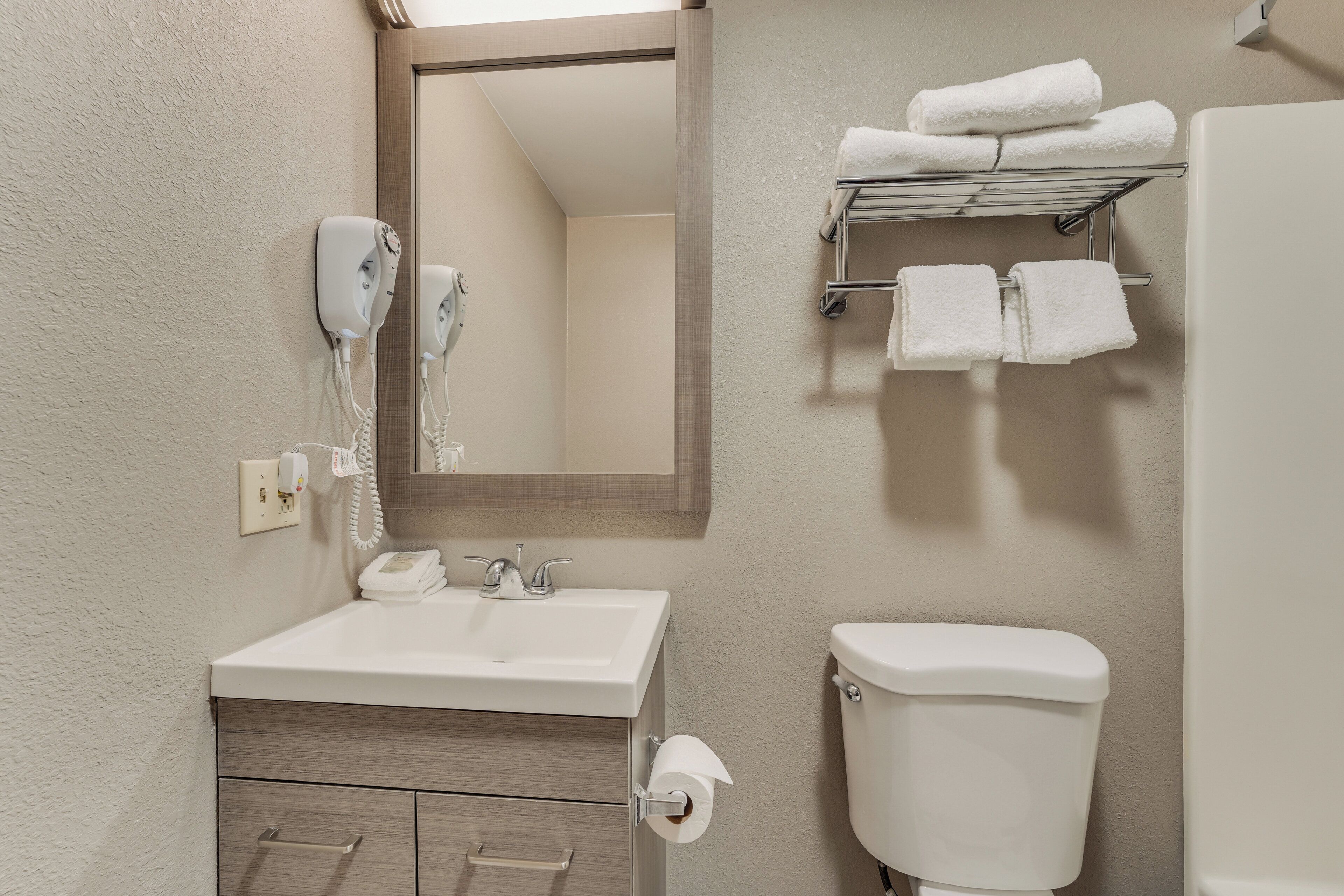 Une salle de bain avec un lavabo blanc, un miroir, des toilettes et un porte-serviettes avec des serviettes.