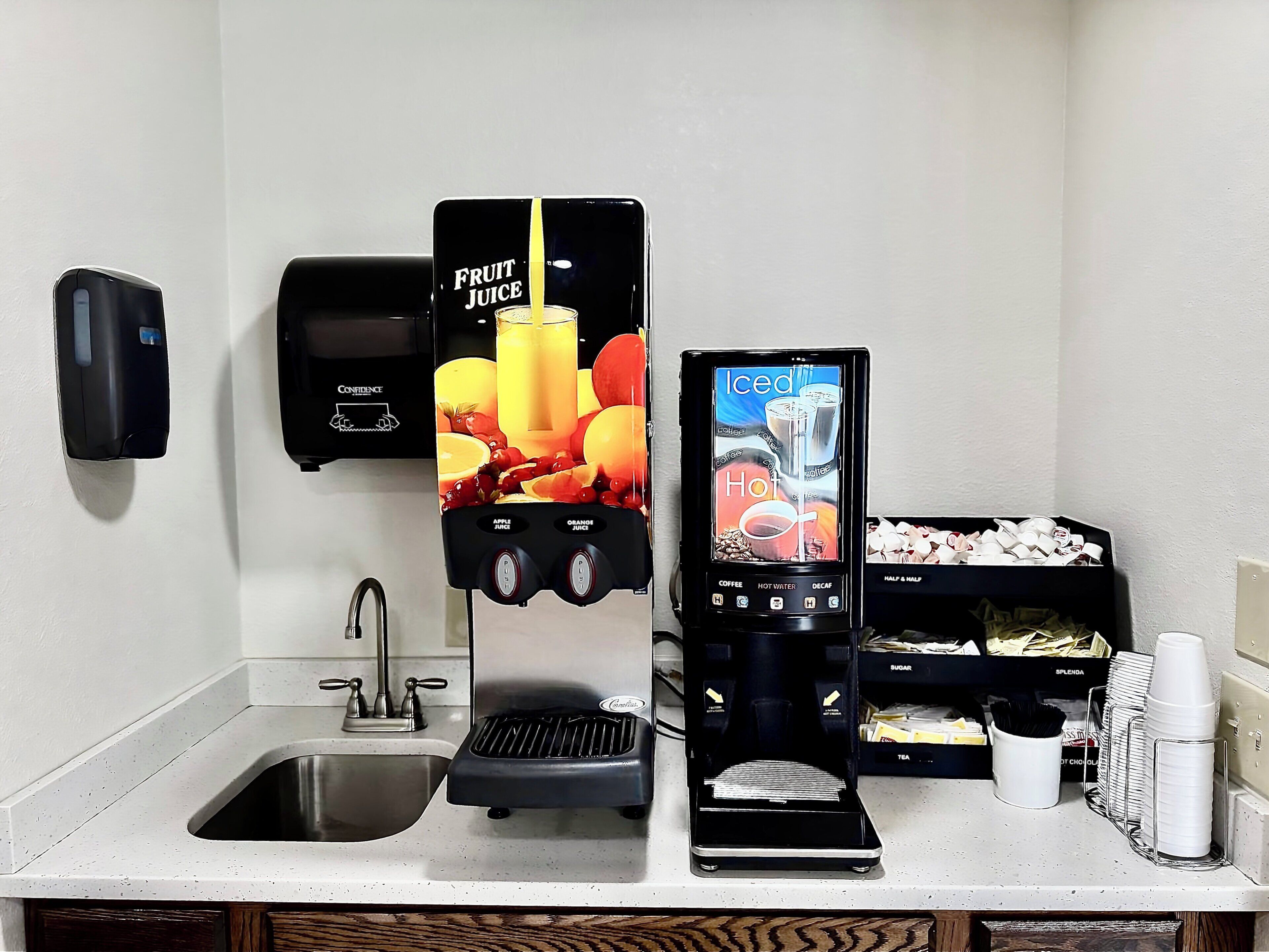 A self-service beverage station with options for fruit juice, iced coffee, hot water, and decaf coffee.