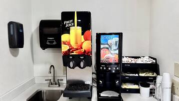 Una estación autoservicio de bebidas que ofrece zumo de frutas, café helado, agua caliente y café descafeinado.
