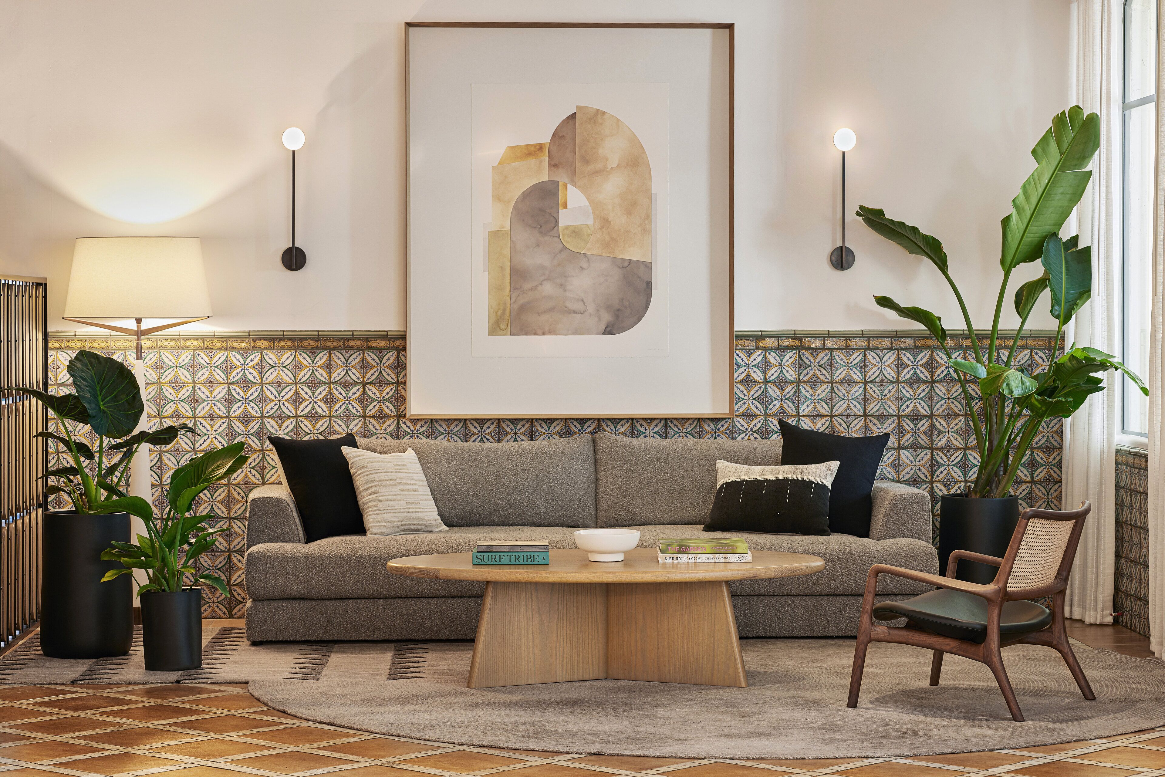 Un salon moderne avec un canapé gris, une table basse ronde et un grand tableau abstrait accroché au mur.