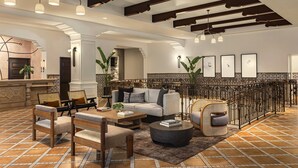 A spacious living area with a sofa, chairs, a coffee table, and a railing with artwork. - Kimpton Canary Hotel by IHG (Santa Barbara)