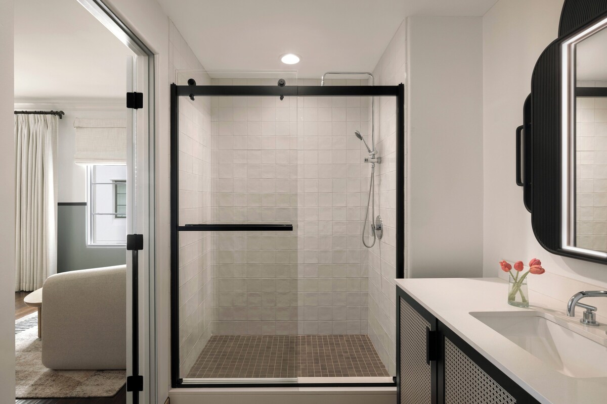 A modern bathroom with a glass-enclosed shower, a white sink, and a mirror above it.