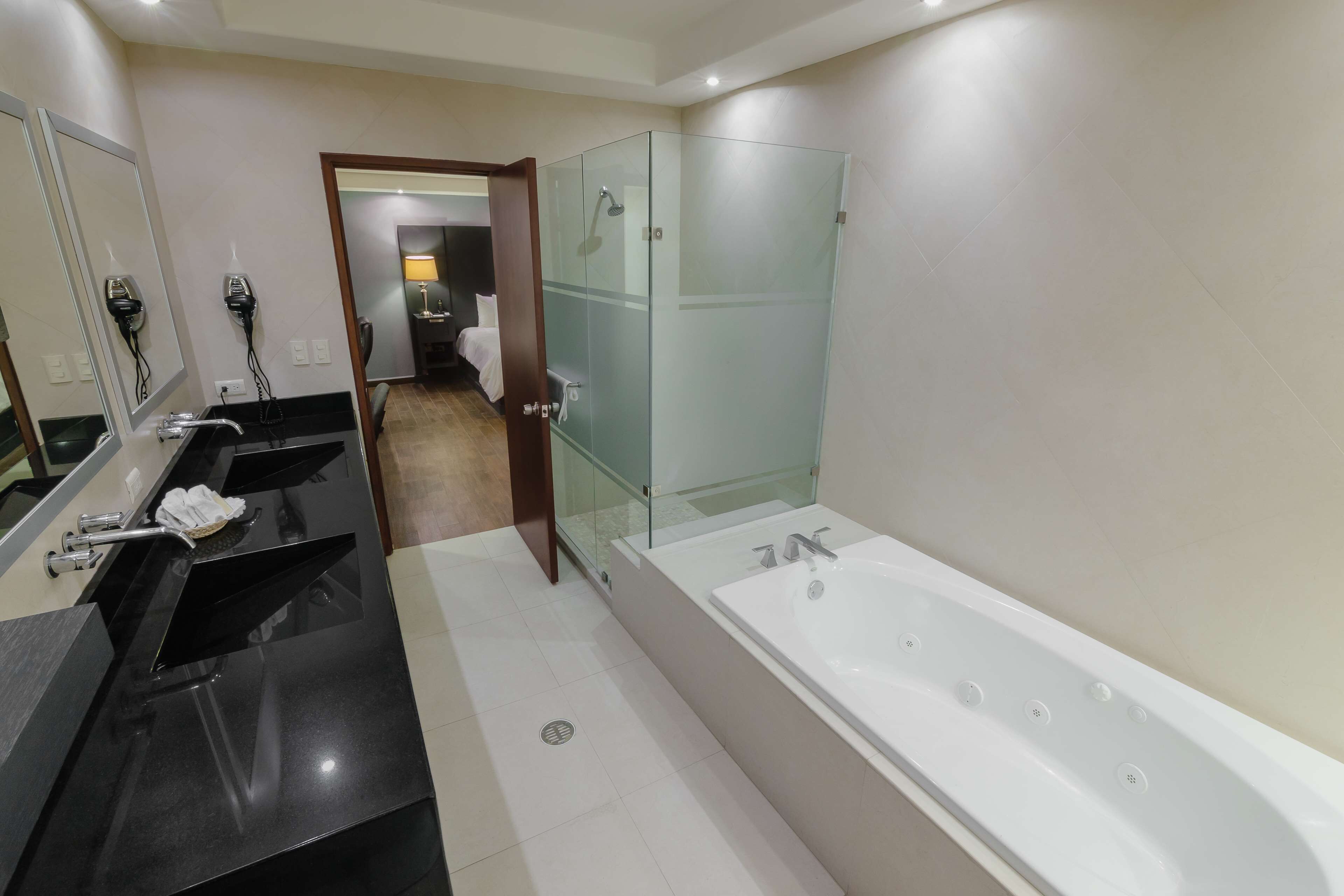 Un baño moderno con una bañera grande, dos lavamanos y una ducha con mampara de vidrio.