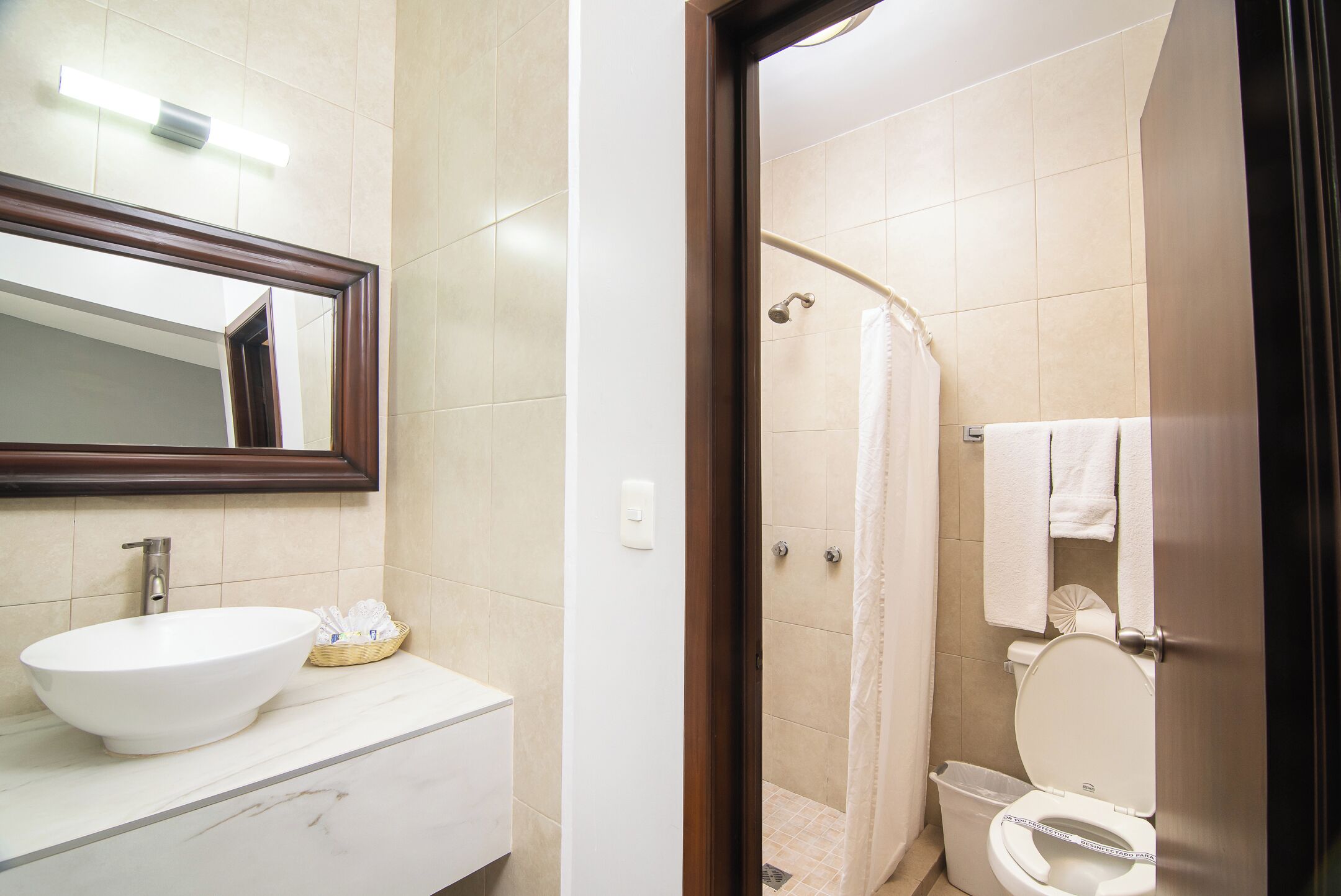 Un baño con un lavamanos blanco, un espejo, una ducha y un inodoro.
