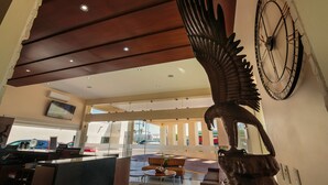 A lobby with a large clock, a reception desk, and a seating area with a view of the street. - Best Western Plus San Jorge (Cajeme)