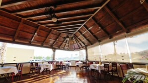 An indoor dining area with wooden flooring and tables, large windows offering a view of the city. - Best Western Plus San Jorge (Cajeme)