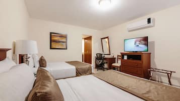 Ein Hotelzimmer mit zwei Betten, einem Schreibtisch, einem Stuhl, einem Fernseher und einer Klimaanlage.