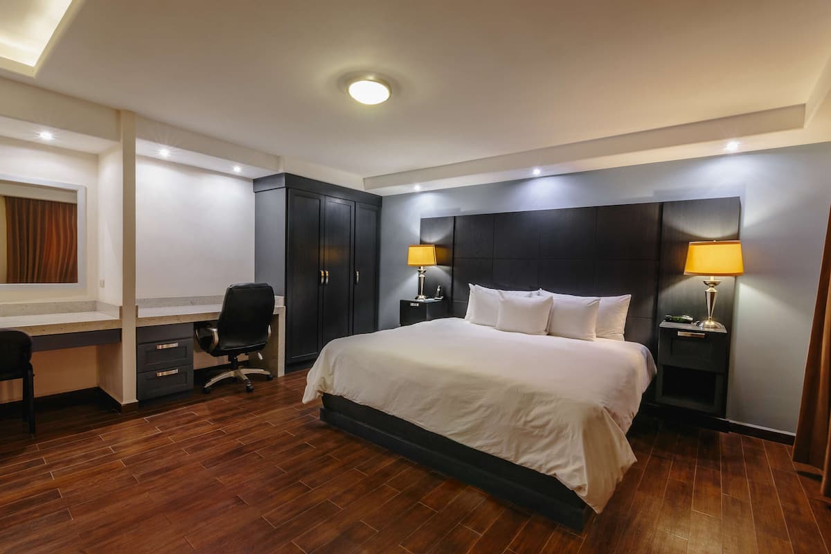 Ein modernes Hotelzimmer mit einem großen Bett, einem Schreibtisch und zwei Nachttischlampen.