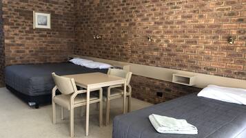 Una habitación con dos camas, una mesita y una silla.