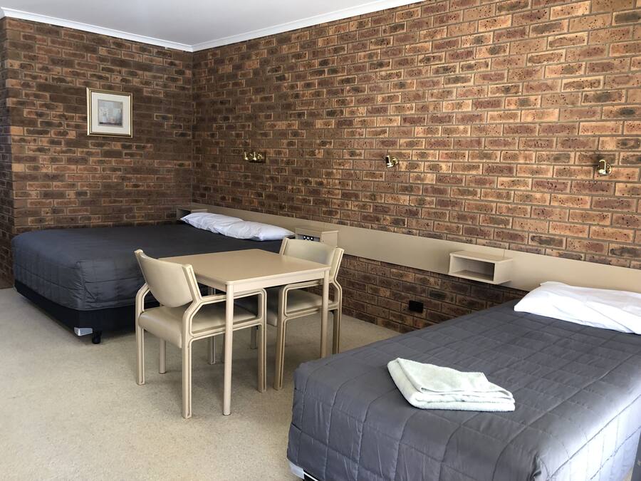 Una habitación con dos camas, una mesita y una silla.