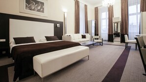 Una camera d'albergo moderna con un letto grande, un divano, una scrivania e uno specchio.
