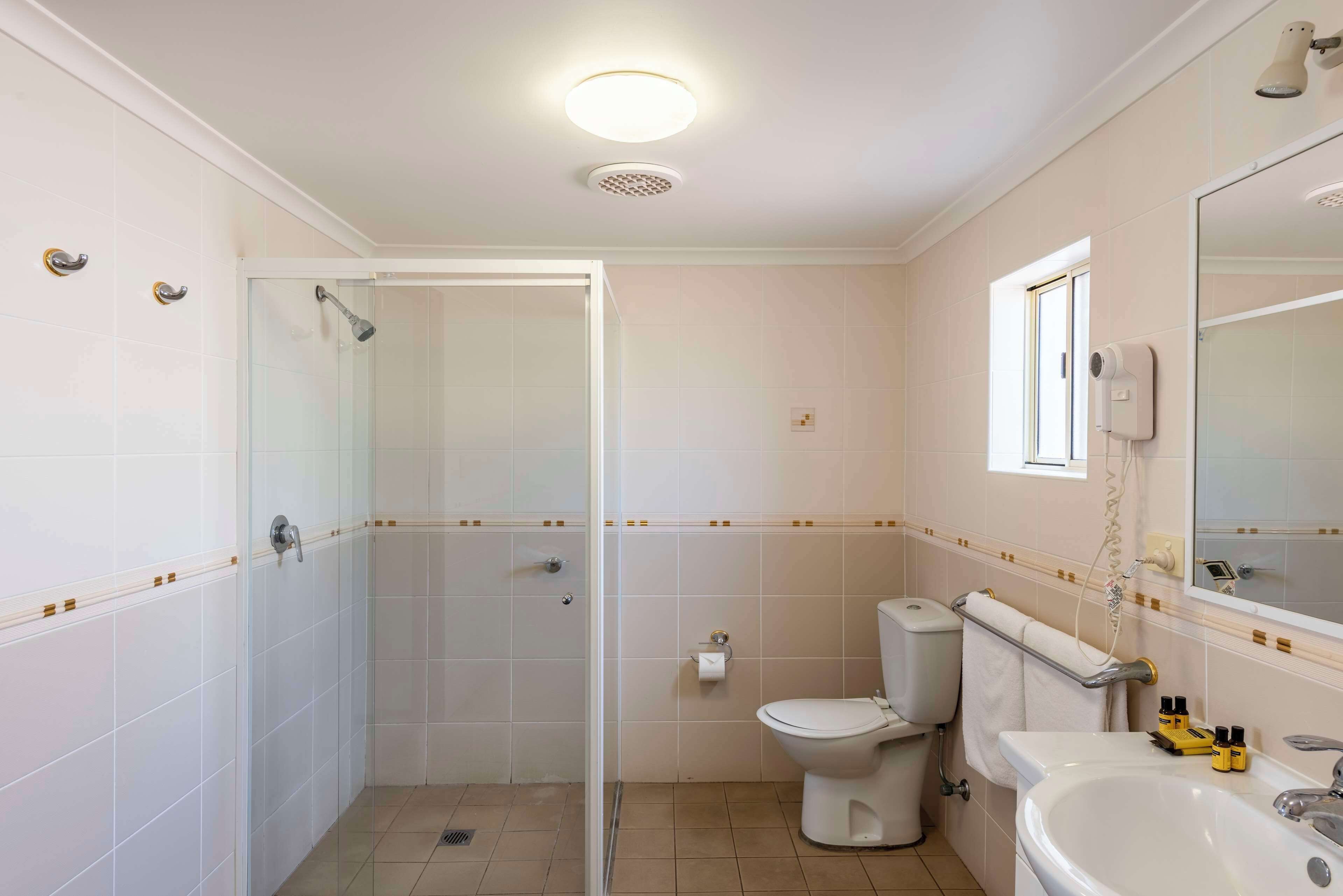 A bathroom with a glass-enclosed shower, a toilet, a sink, and a mirror.