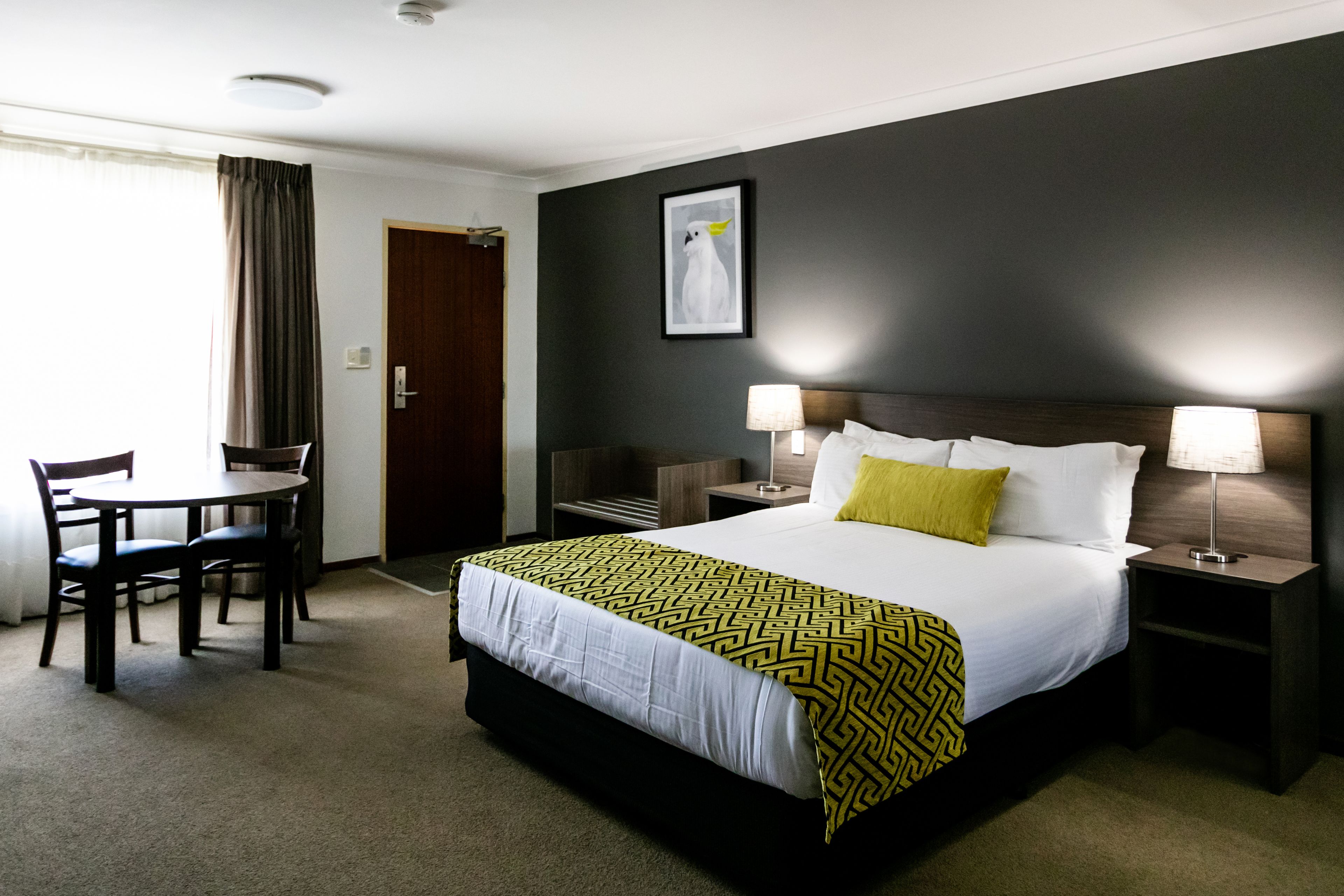 A hotel room with a bed, bedside tables, a desk, and chairs.