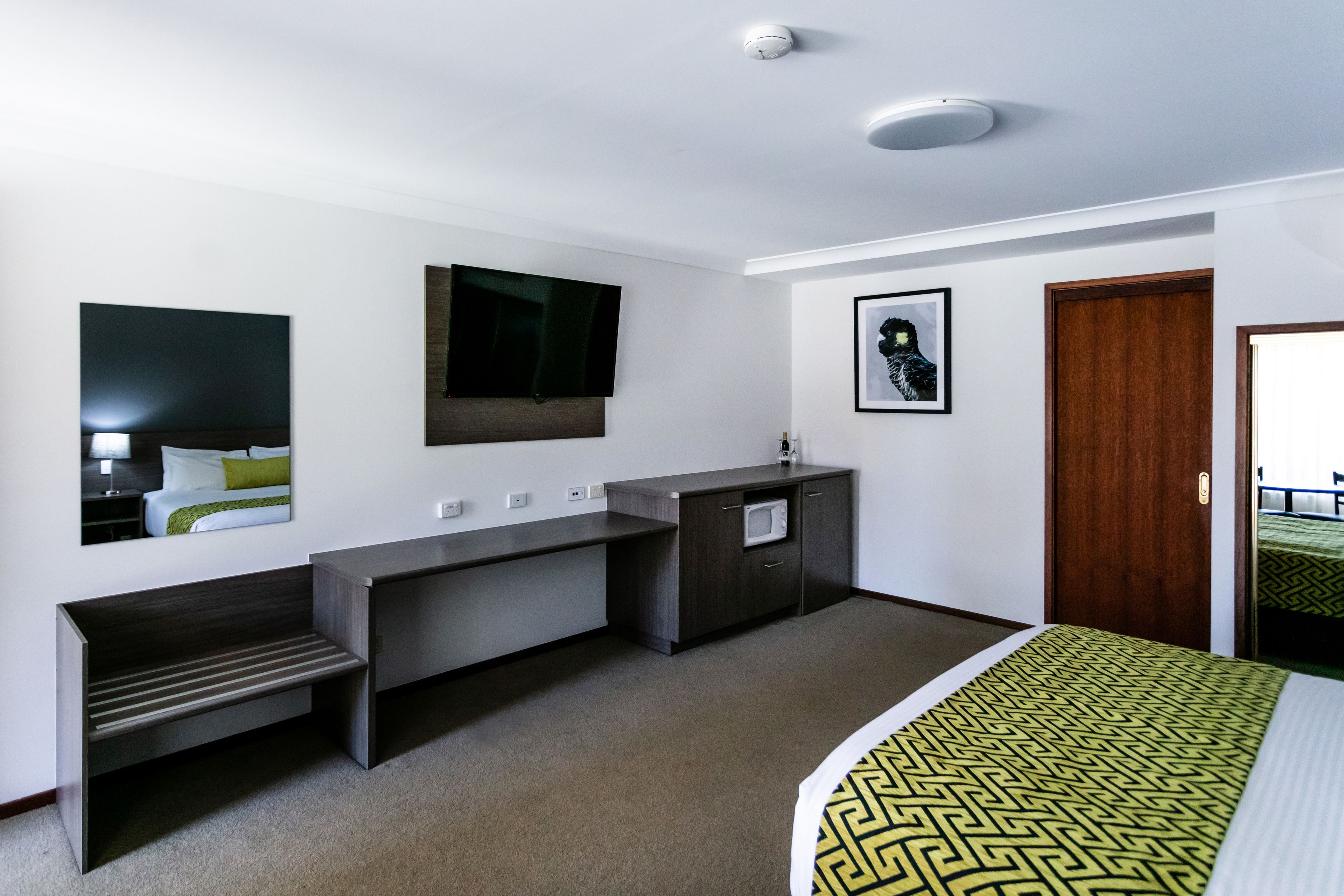 Una habitación de hotel con cama, escritorio, televisión, microondas y puerta.