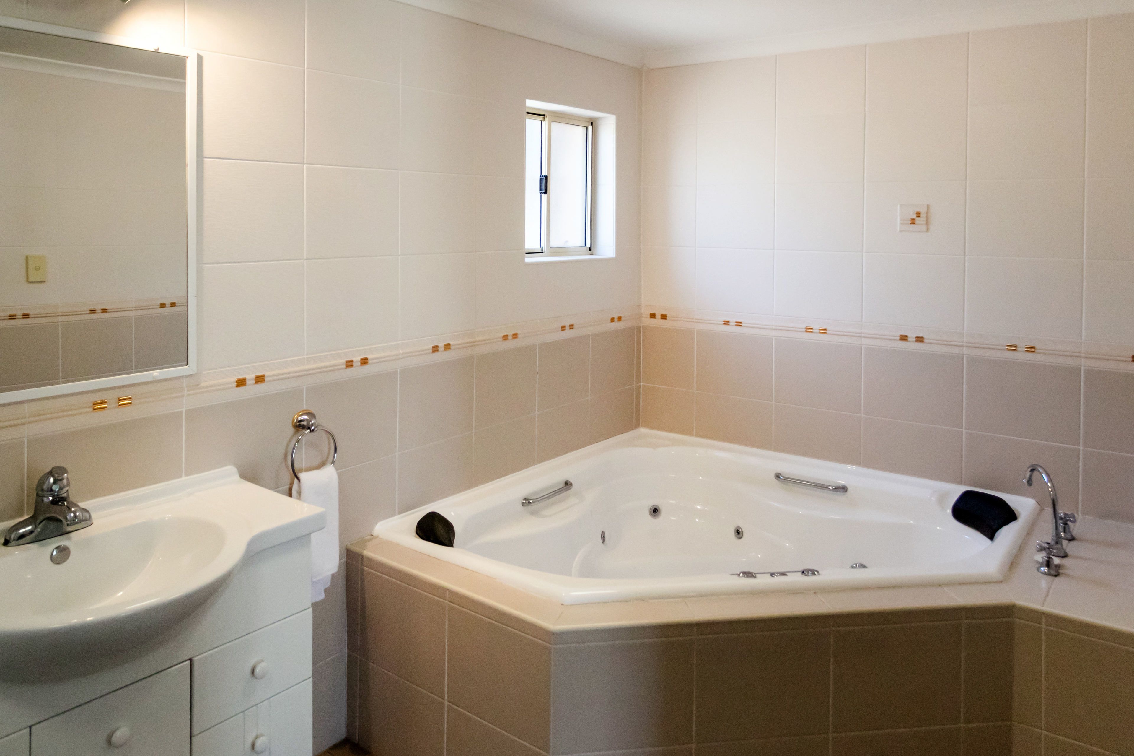 Une salle de bain avec une grande baignoire, un lavabo et une fenêtre.