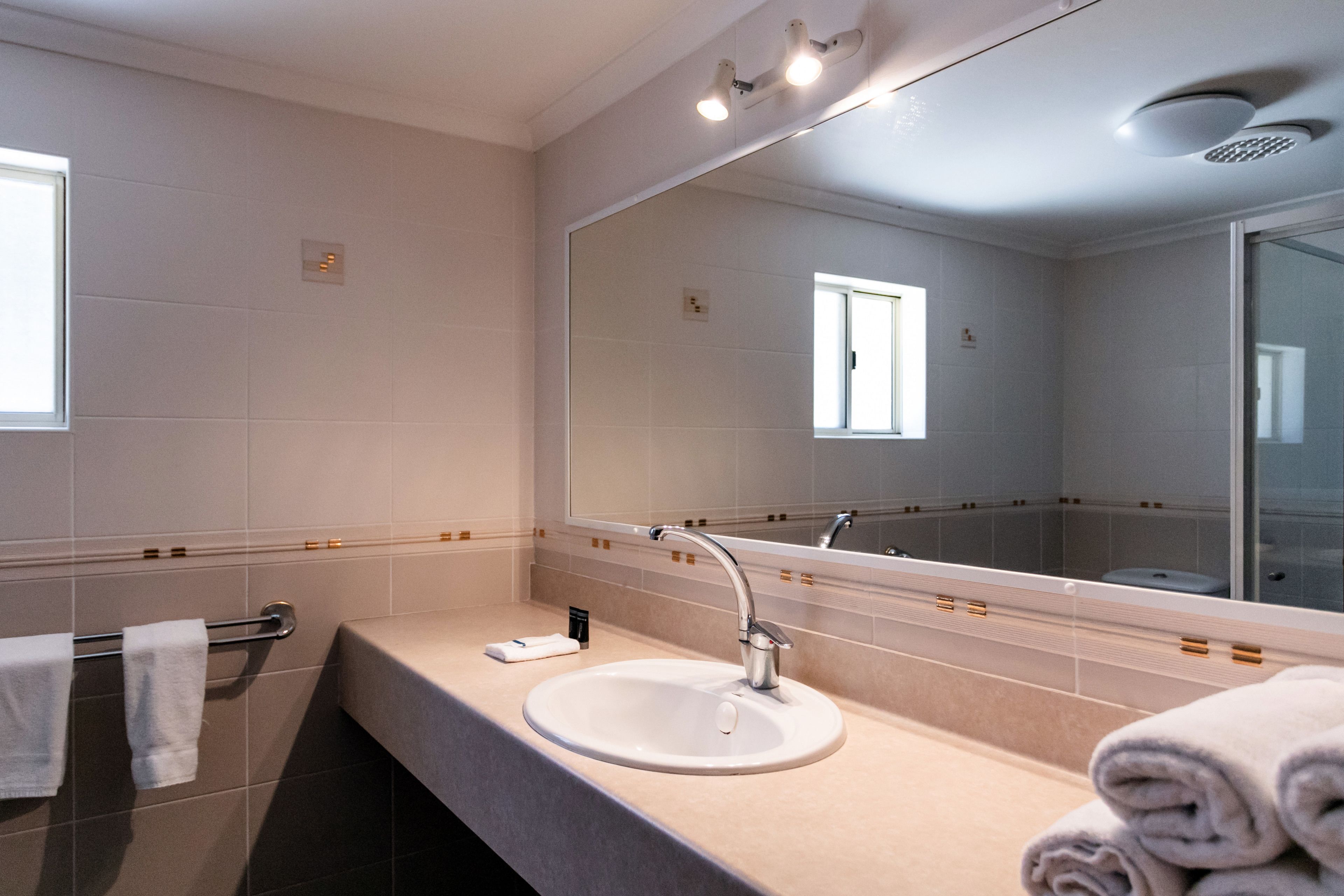 A modern bathroom with a large mirror, a sink, and a towel rack.