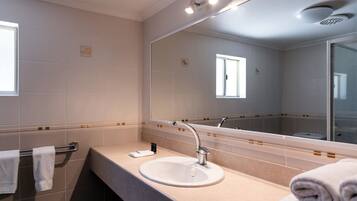 Een moderne badkamer met een grote spiegel, een wastafel en een handdoekhouder.