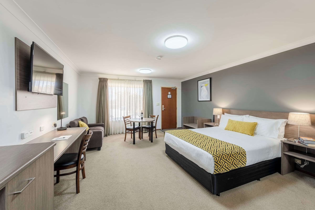 A hotel room with a bed, desk, chair, and a TV.