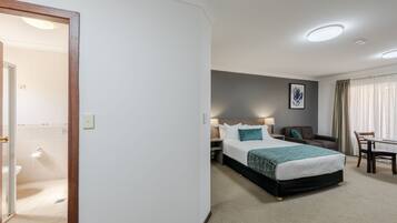 Ein Hotelzimmer mit Bett, Schreibtisch, Stuhl, Sofa und einem durchgegangenen Tür sichtbaren Badezimmer.