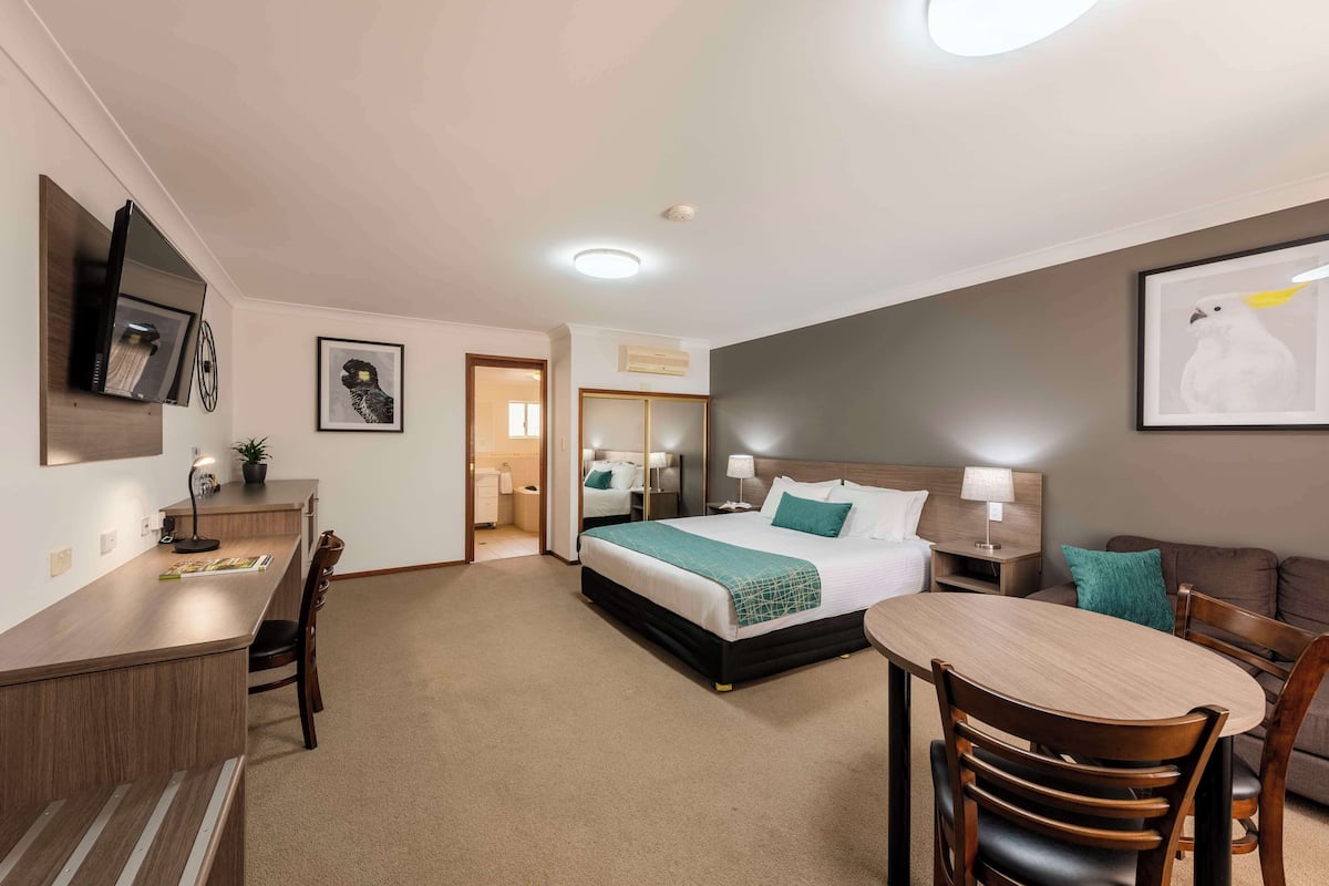 A hotel room with a bed, desk, and seating area.