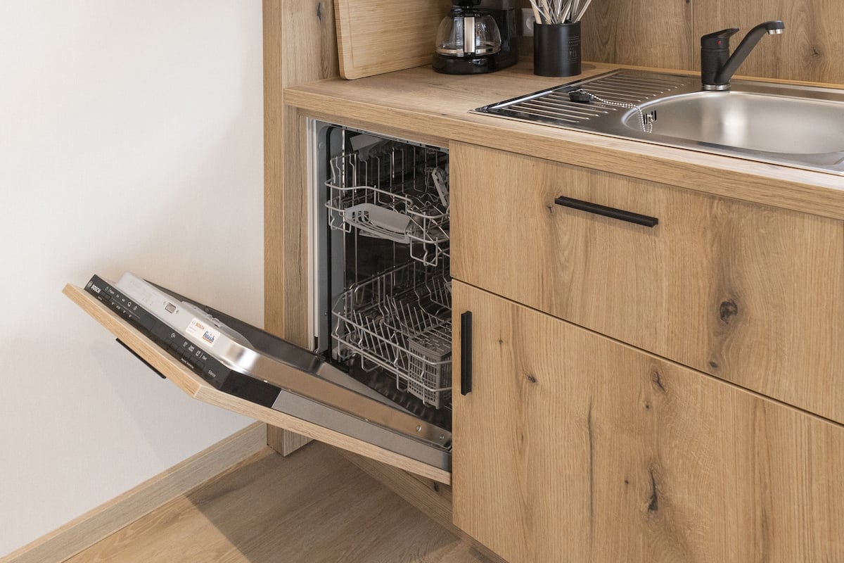Una cocina equipada con lavavajillas, un fregadero y muebles de madera.