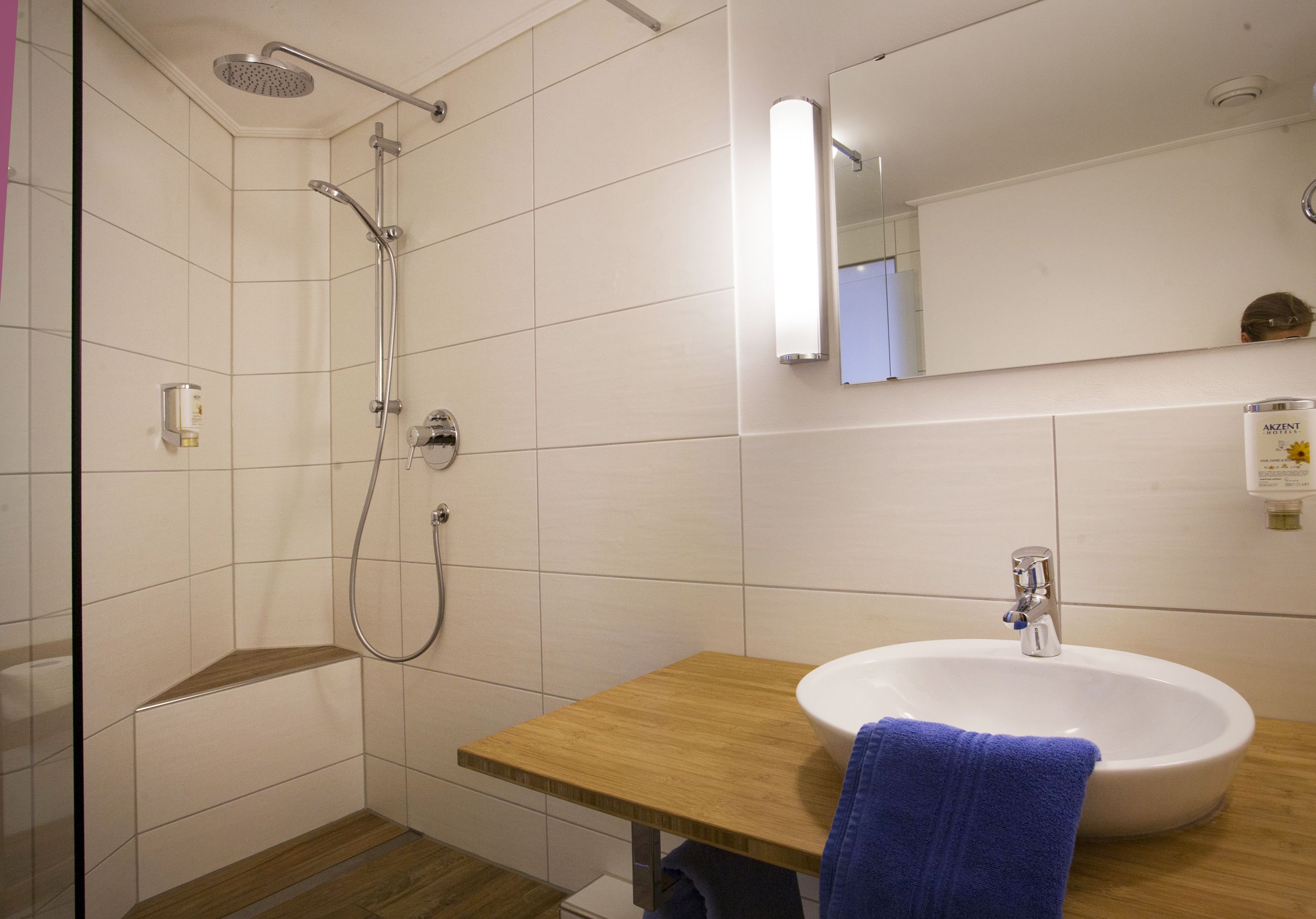 Un baño con ducha, lavamanos y espejo.