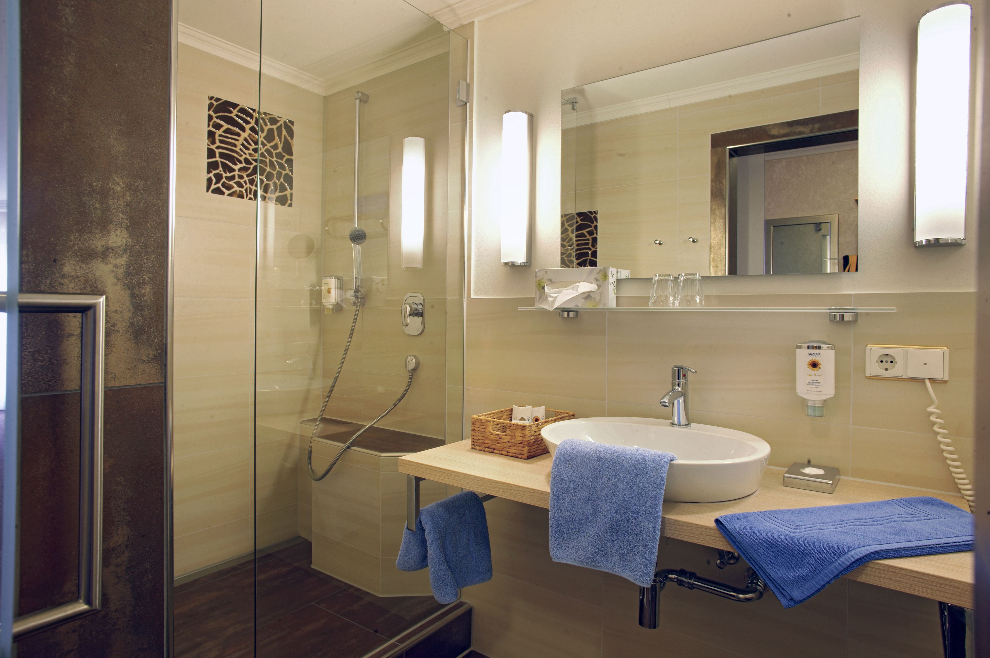 A modern bathroom with a glass-enclosed shower, a sink with a towel, and a mirror.
