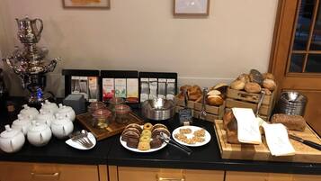 A buffet with various food items, including pastries, cookies, and a selection of beverages.