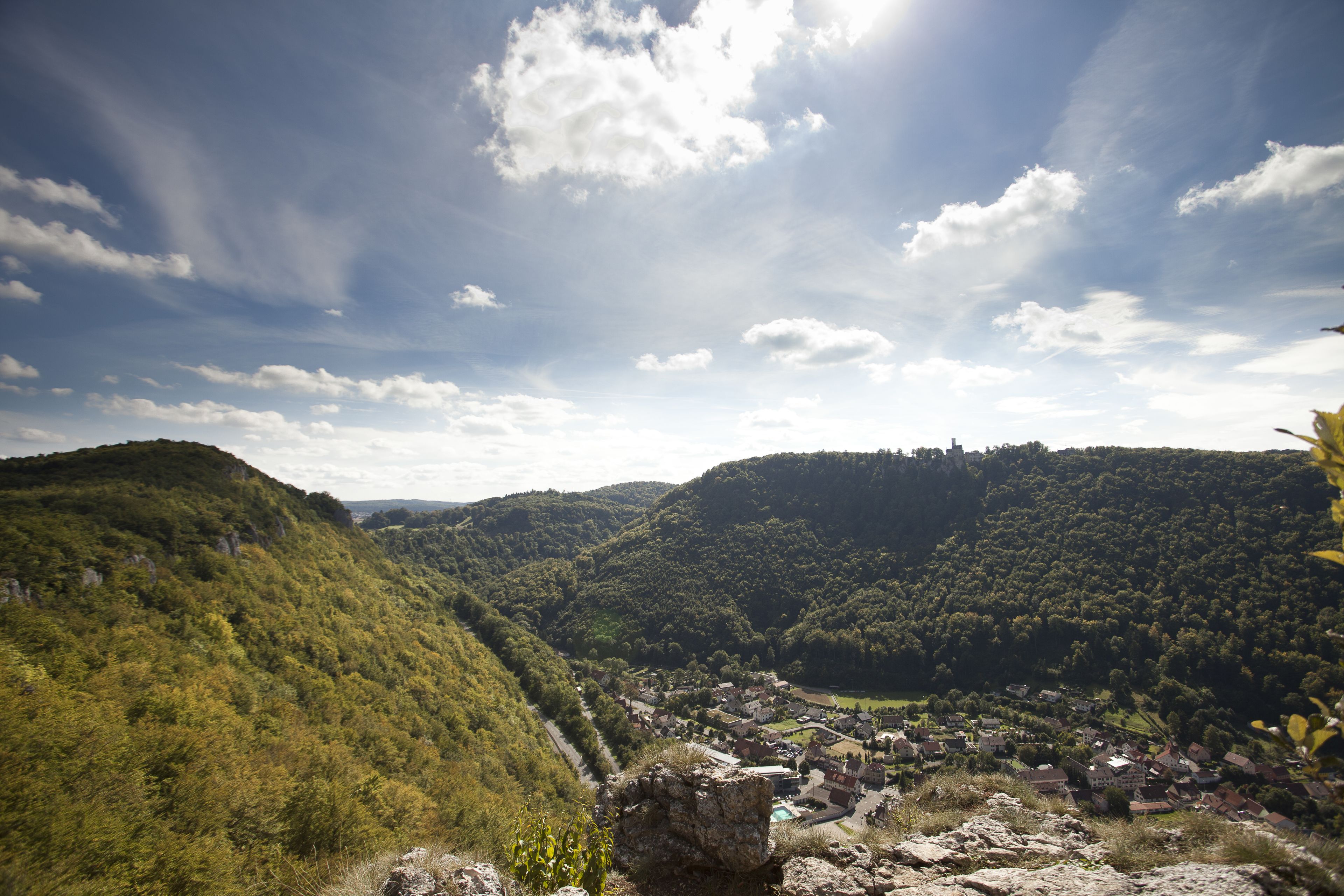 Une vallée où se trouve un village, entourée de collines et d’une forêt dense.