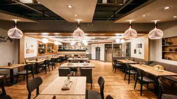 Un restaurante amplio con varias mesas y sillas, iluminación colgante y un diseño de interiores moderno.