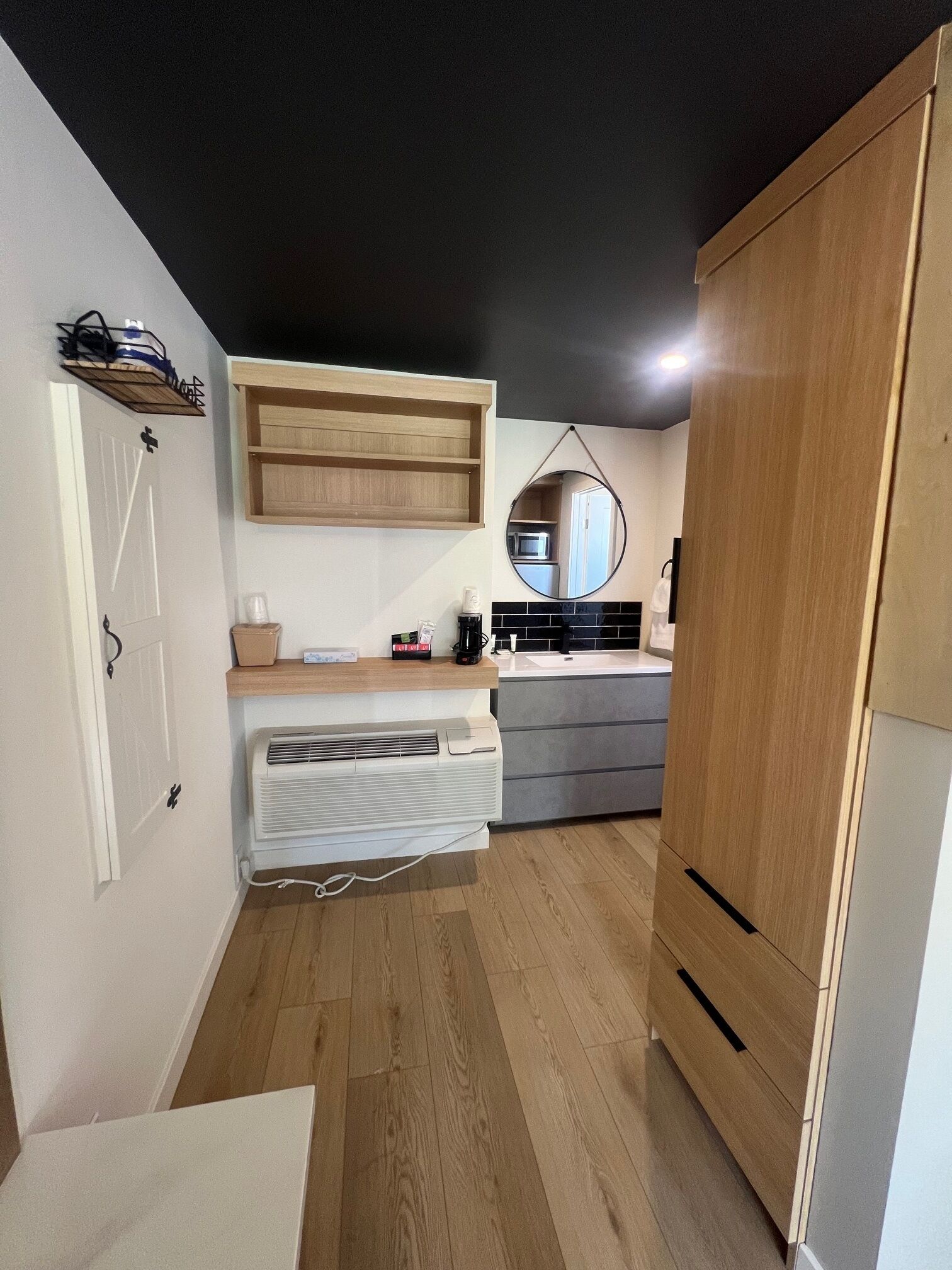 Una cocina compacta con microondas integrado, un mueble de madera y una pequeña encimera.