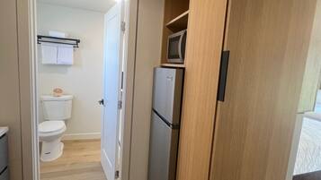 A compact kitchen with a wooden cabinet, a refrigerator, and a microwave.