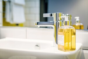A bathroom sink with a mirror, a chrome faucet, and a bottle of liquid soap.