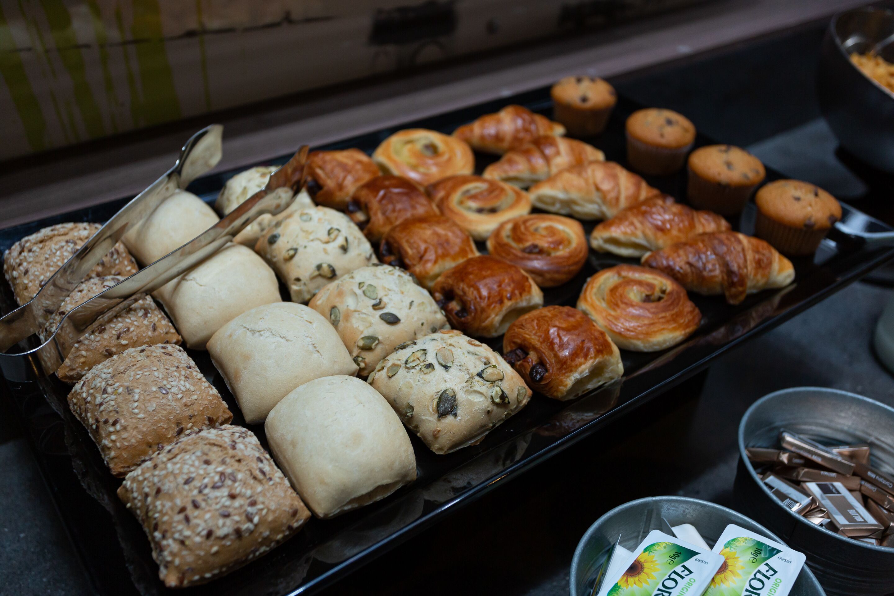 Una bandeja con una variedad de productos horneados, como panecillos, croissants y muffins.