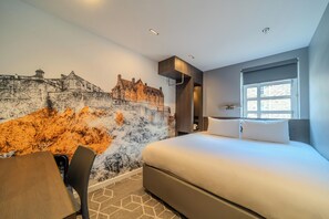 Quarto de hotel moderno com uma cama grande, uma mesa de jantar e um mural de um castelo.