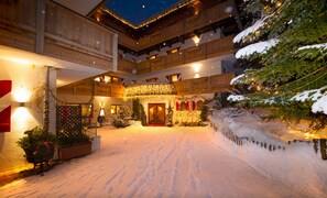 A hotel lobby with a snow-covered ground, wooden architecture, and Christmas decorations. - Landhof Ellmau (Ellmau)