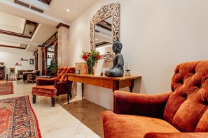 A spacious lobby with a wooden reception desk, a large mirror, and plush seating. - Hotel Bruggwirt (Sankt Johann in Tirol)