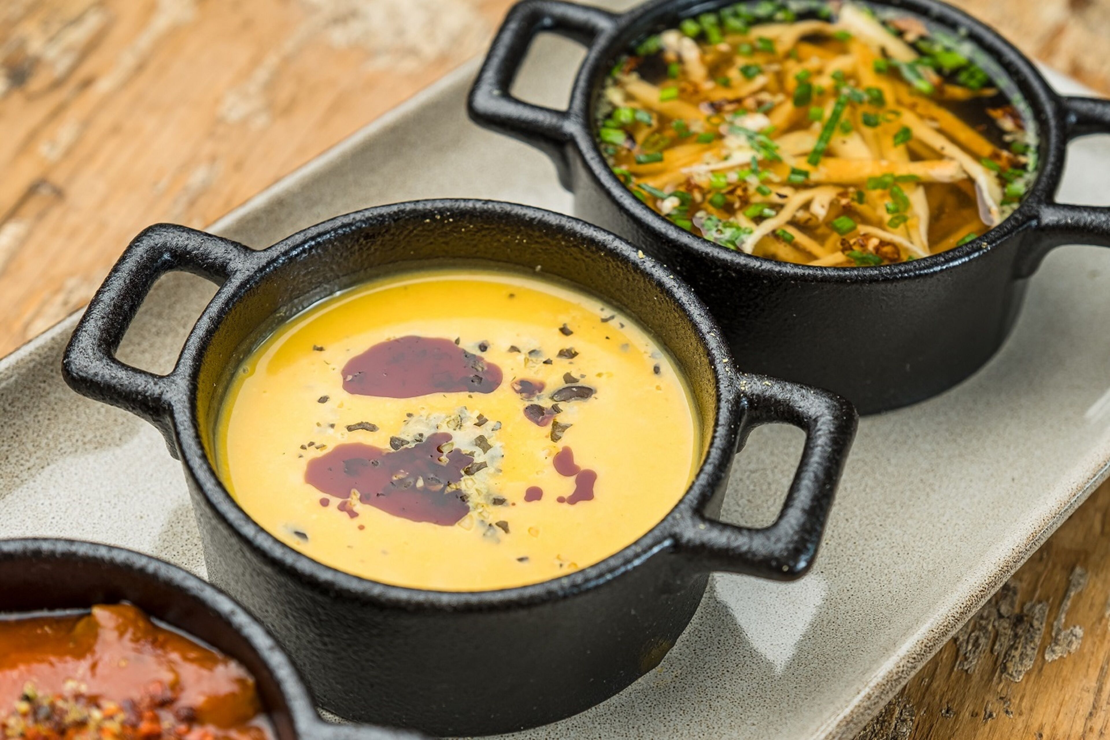 Three black cast iron pots with different dishes on a tray.