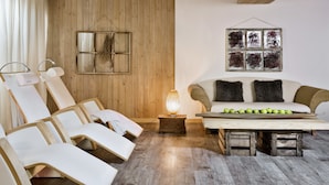 Una habitación con paneles de madera, un sofá blanco con cojines oscuros, una mesa de centro de madera con manzanas, y una obra de arte abstracto colgada en la pared.