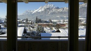 Vista de una cadena montañosa nevada desde una ventana con marcos de madera.