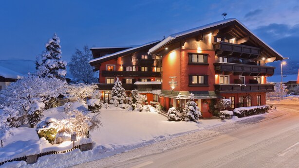 Un hotel de varios pisos con fachada nevada y ventanas iluminadas.