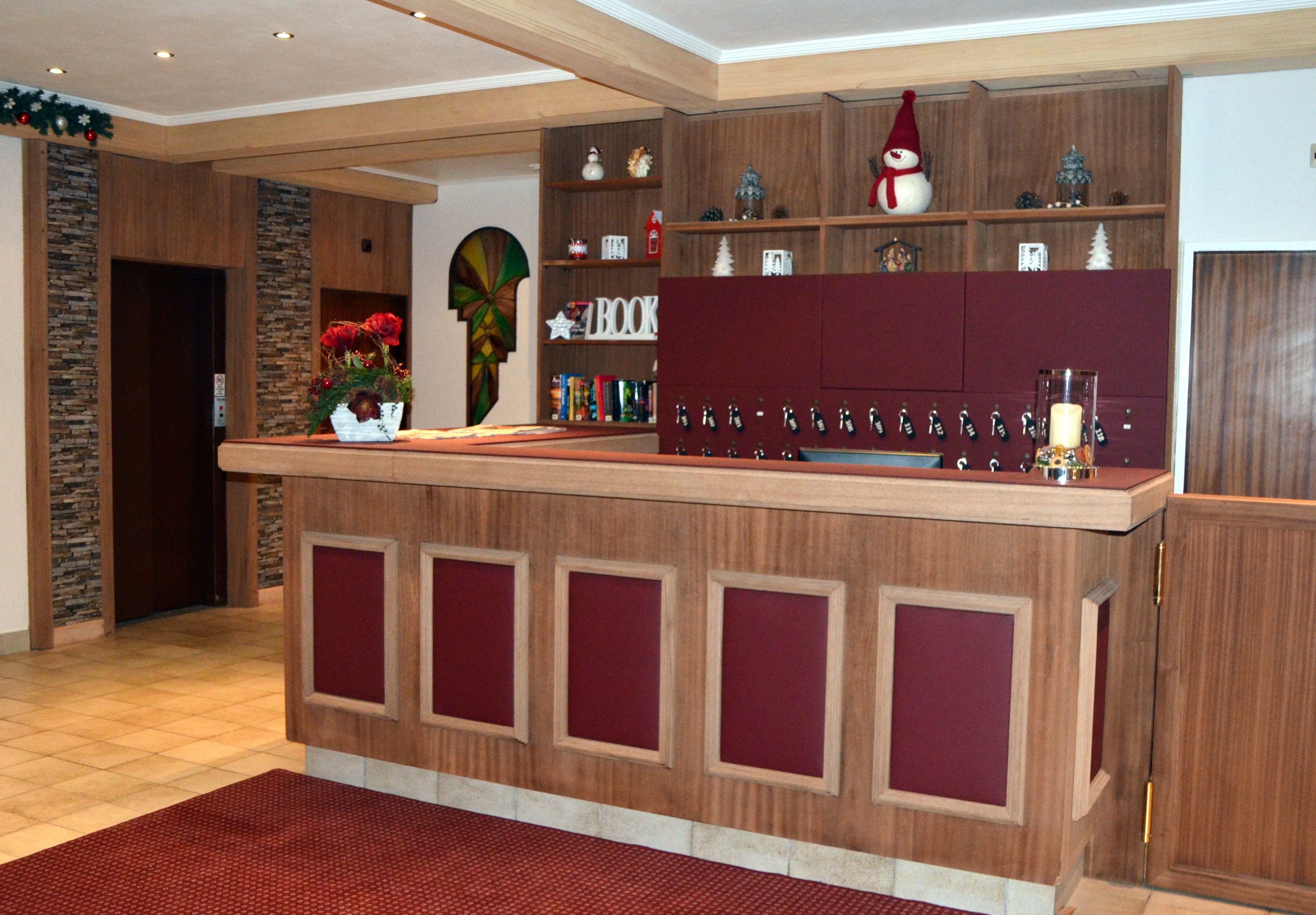 A reception area with a wooden counter, a red carpet, and a Christmas decoration.