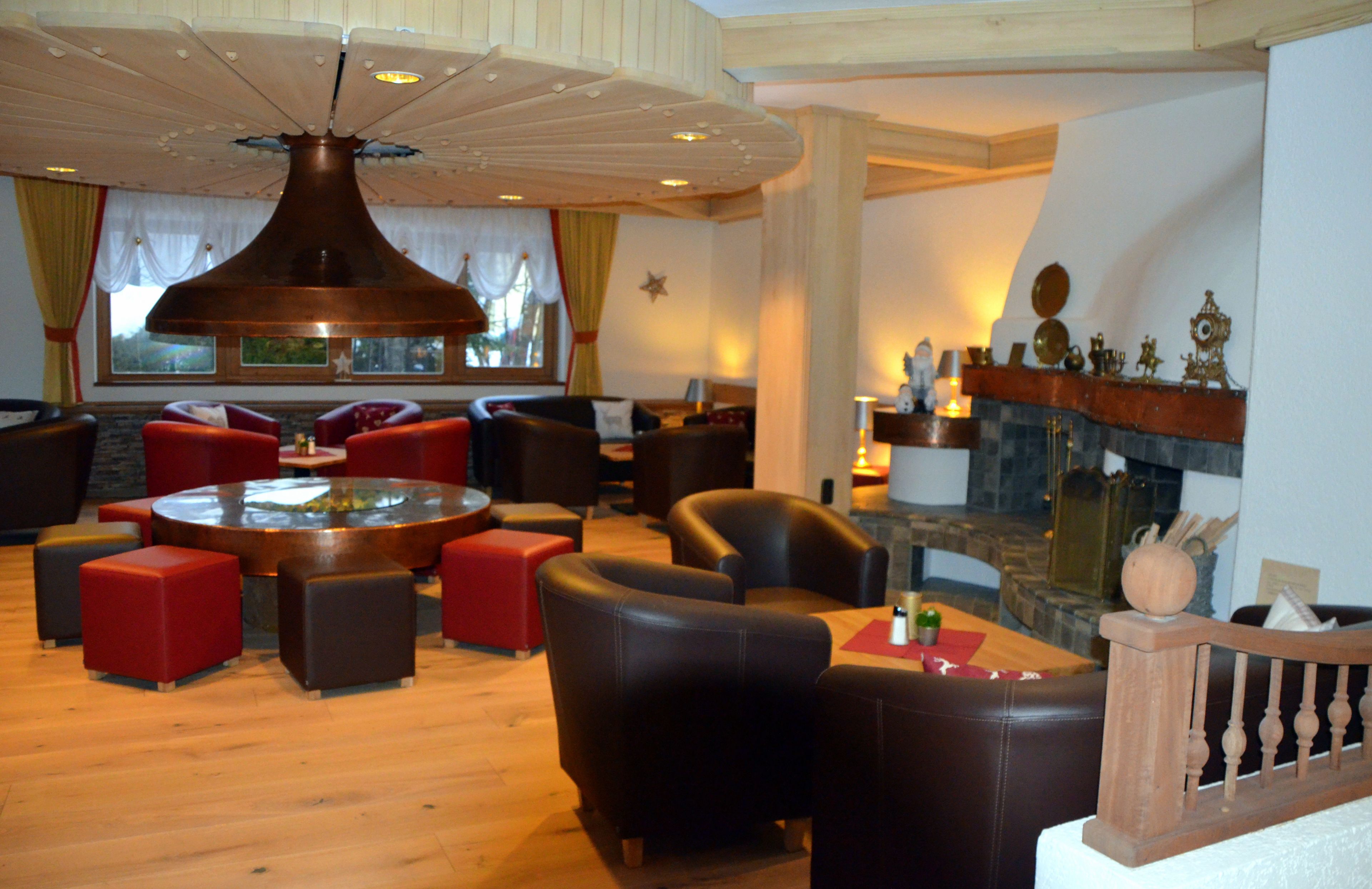 A modern living room with a large round table, leather sofas, and a fireplace.