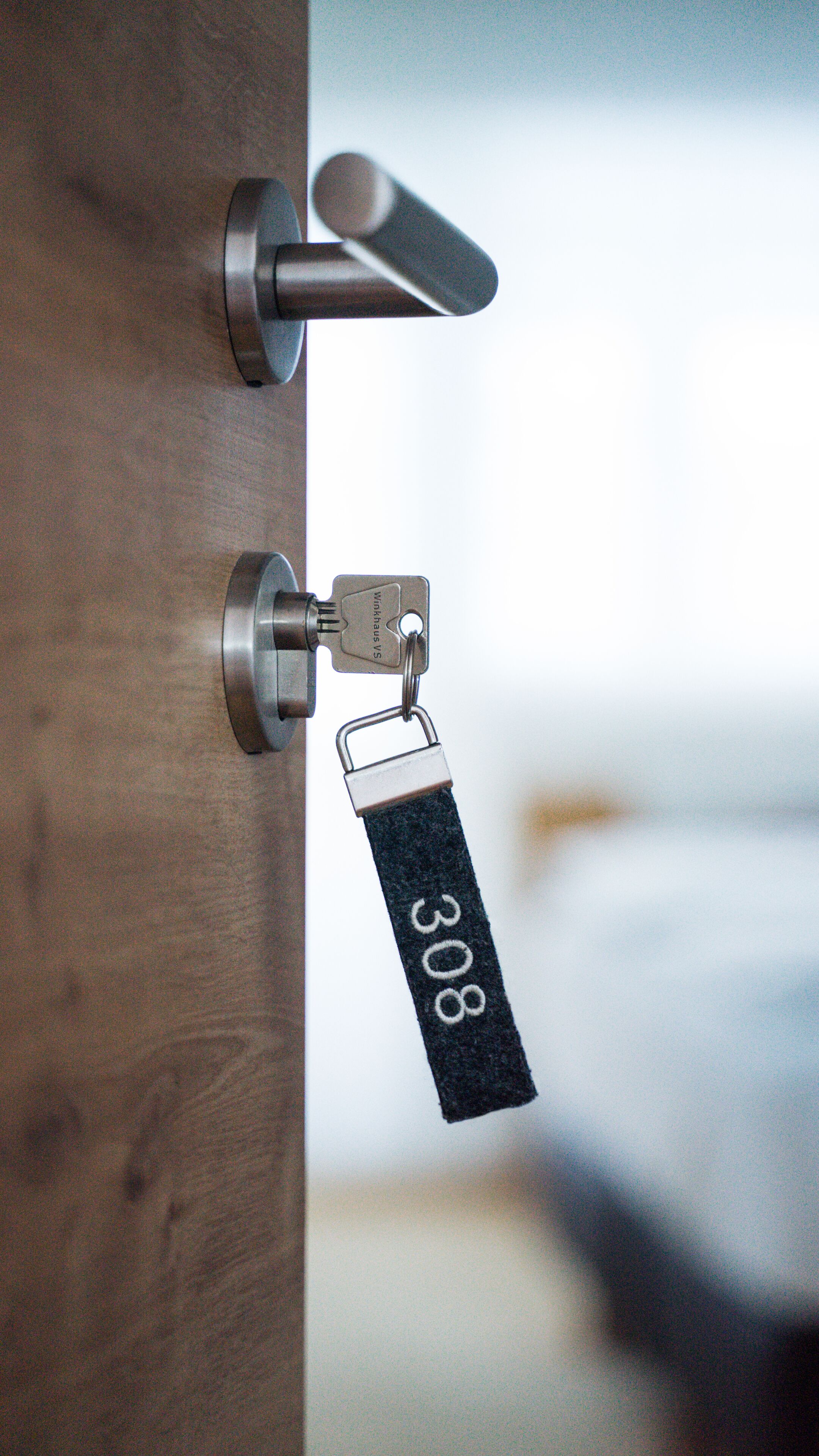 Une serrure de porte avec un trou de serrure et une plaque métallique portant le numéro « 308 ».