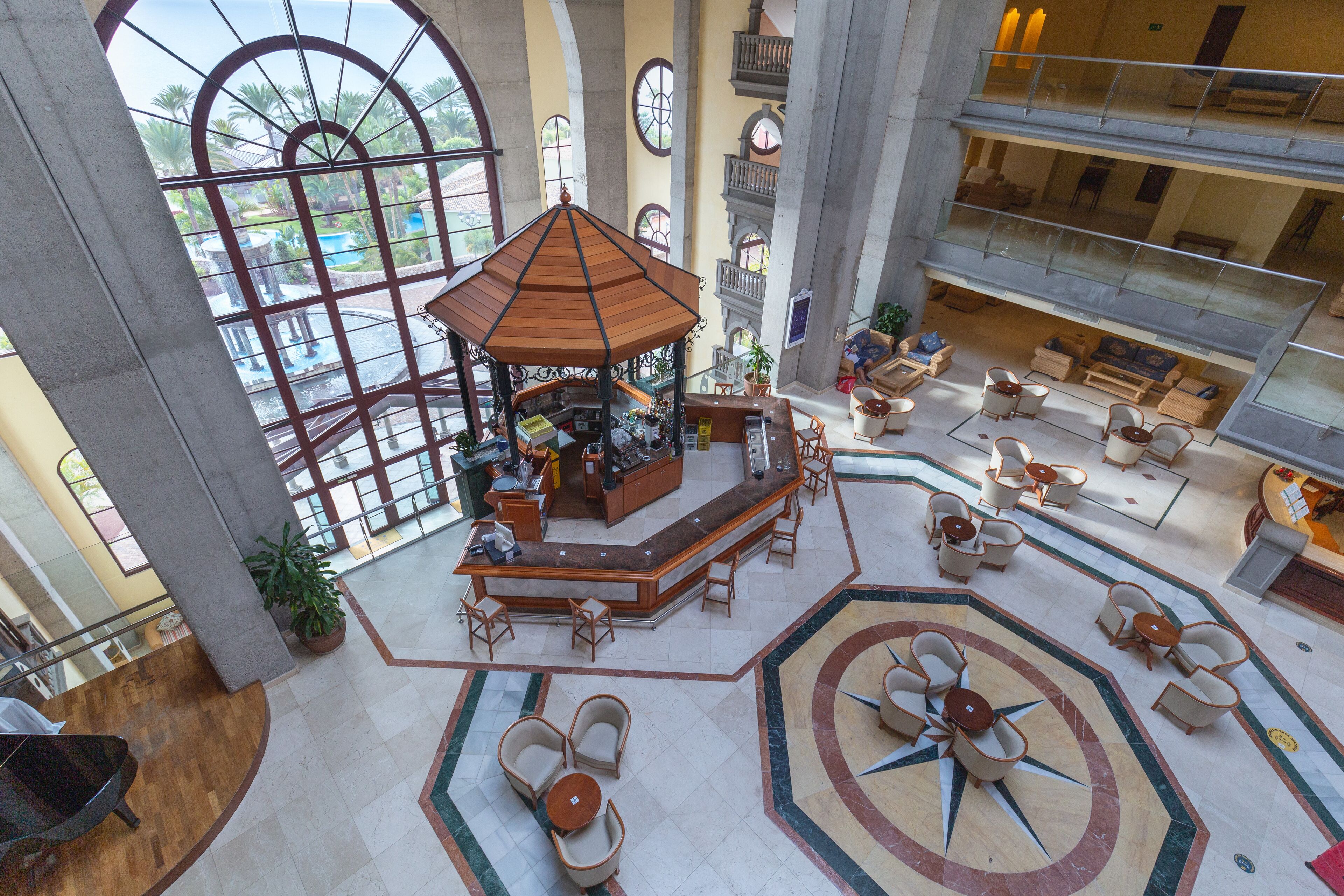 Un hall amplio con una zona de estar central, vista a la piscina y varios pisos con balcones.
