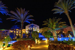 Et veloplyst hotel med pool, palmer og en belagt sti.