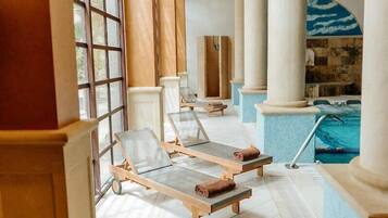 Ein sonnendurchfluteter Poolbereich mit Liegestühlen, einem kleinen Pool und Blick ins Freie.