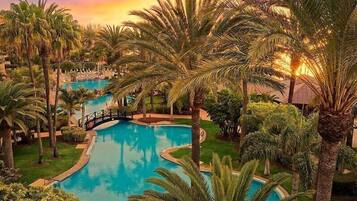 Un resort con piscina rodeada de palmeras y un puente.
