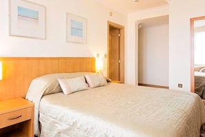 A neatly made bed in a hotel room with a wooden headboard, a nightstand, and two framed pictures on the wall. - Carousel Hotel (Blackpool)
