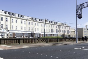 A row of white buildings with signs for a cafe bar, carousel, and celebration suite. - Carousel Hotel (Blackpool)